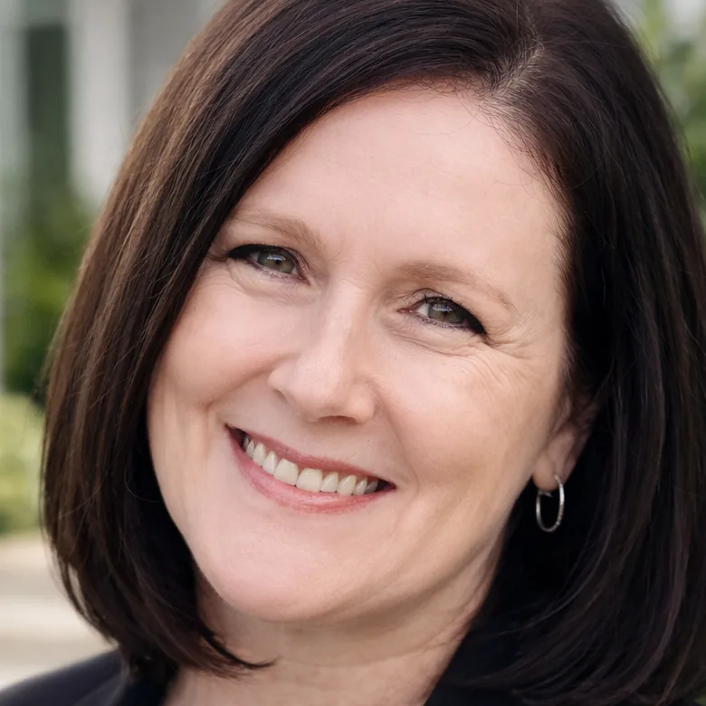 Amanda van Staden, with a dark bob, wearing a black blazer and a floral top.