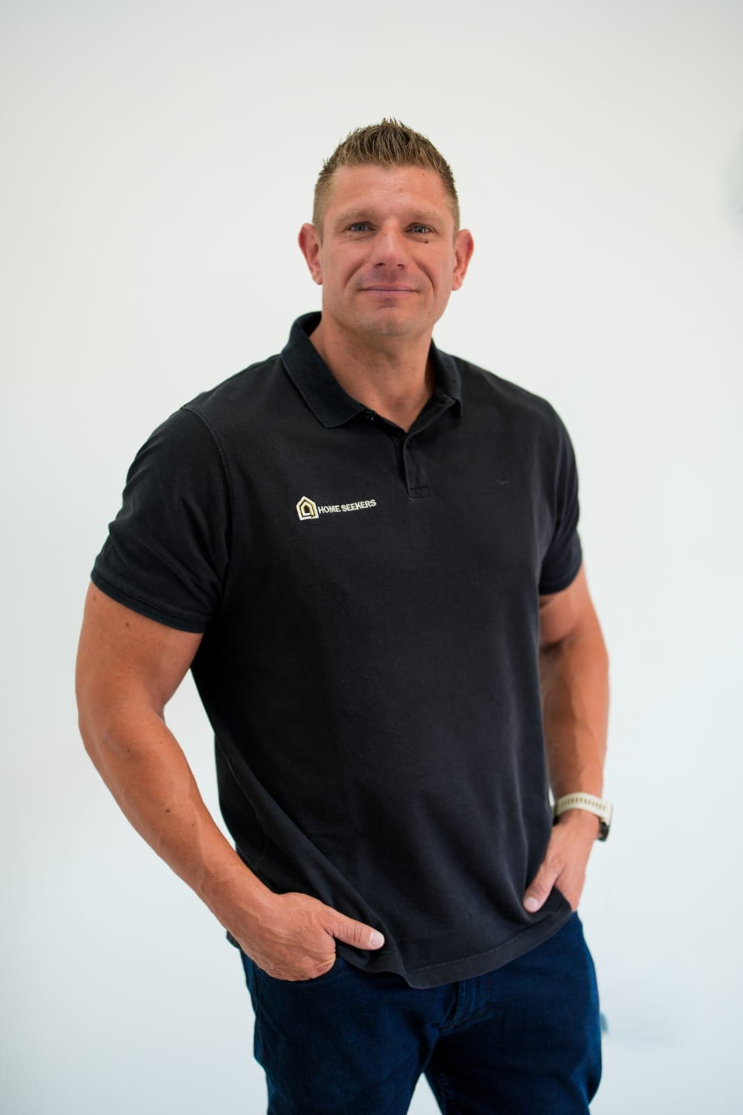 Thomas Potgieter, founder of Home Seekers, in a black Home Seekers polo against a white wall.